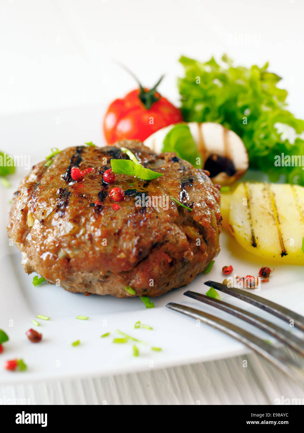 Succulente manzo cotto burger con potatoe e insalata su una piastra bianca. Foto Stock