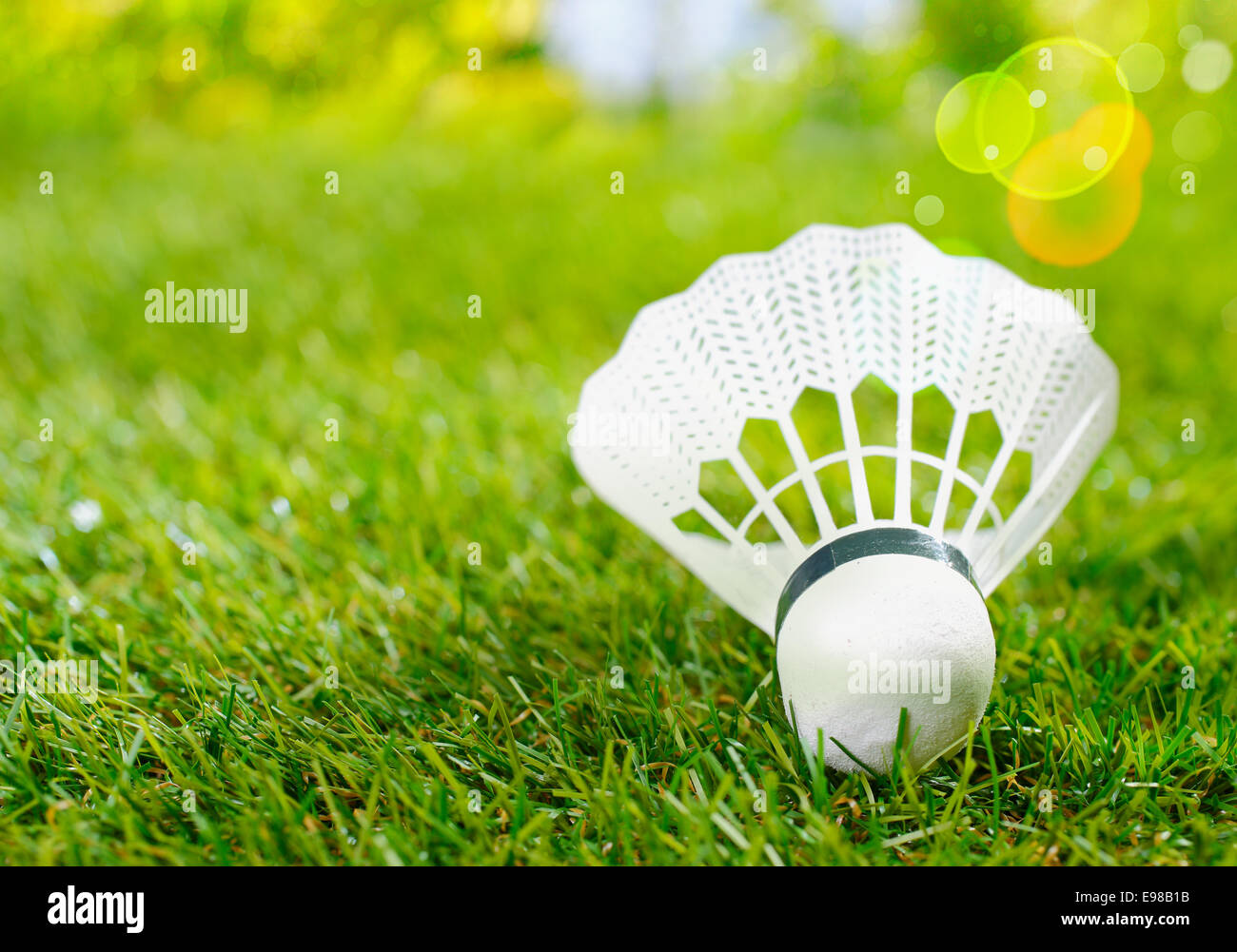 Primo piano dettagliato di un campo di badminton volano con le piume di plastica giacente su erba verde in estate al sole con copyspace Foto Stock