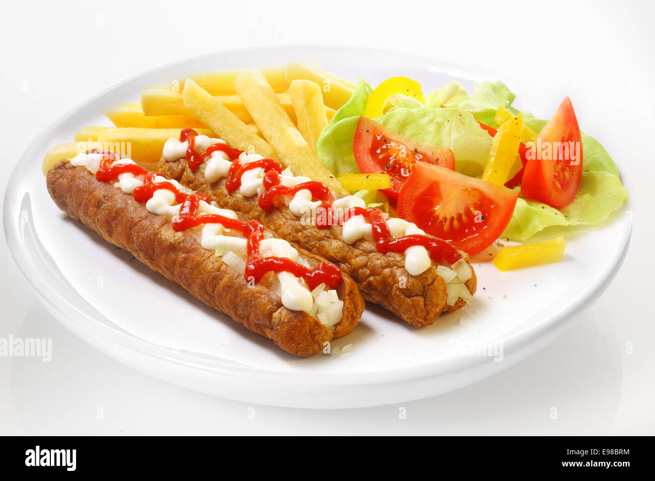 Frikandel grigliate di salsicce affumicate e rabboccato con una decorazione a zig-zag medicazione di maionese e tomato ketchup servito con insalata e patatine fritte in una pianura piastra bianca Foto Stock
