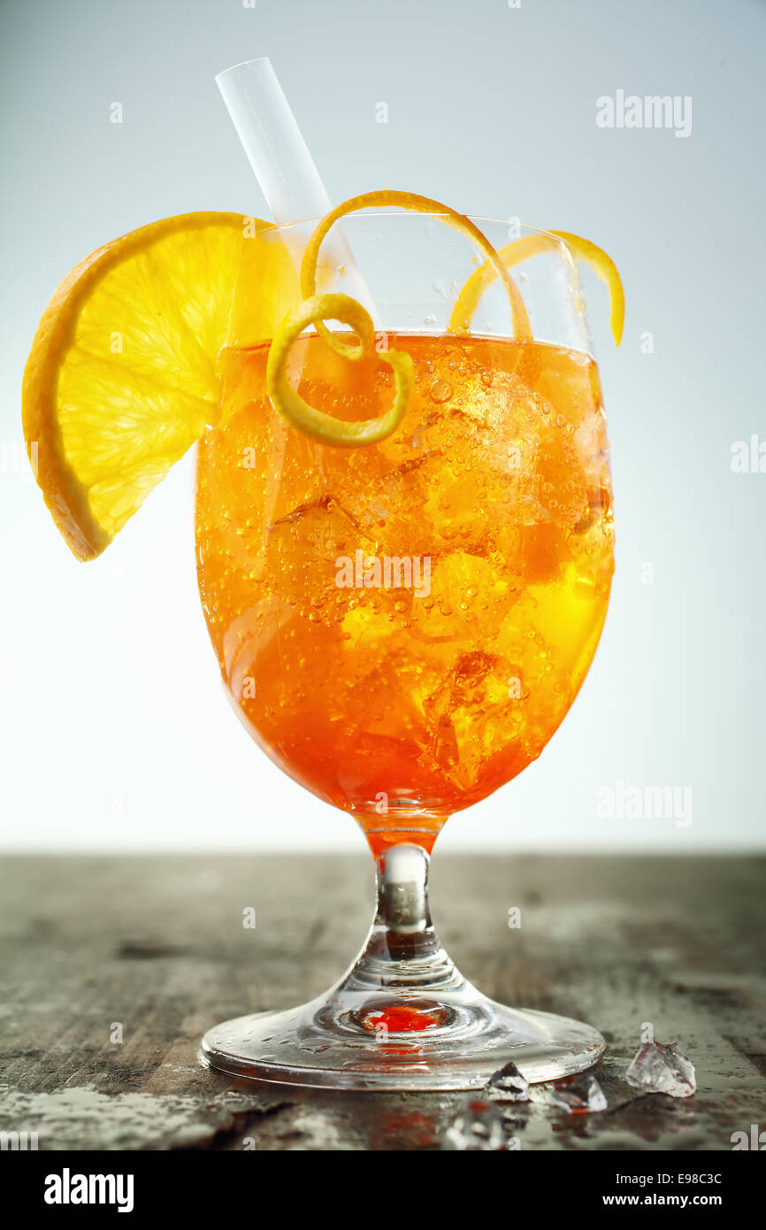Colorato iced rum e cocktail arancione guarnite con fettine di arancia e la cotenna in piedi su una barra di legno con contatore di spandimento in piedi Foto Stock