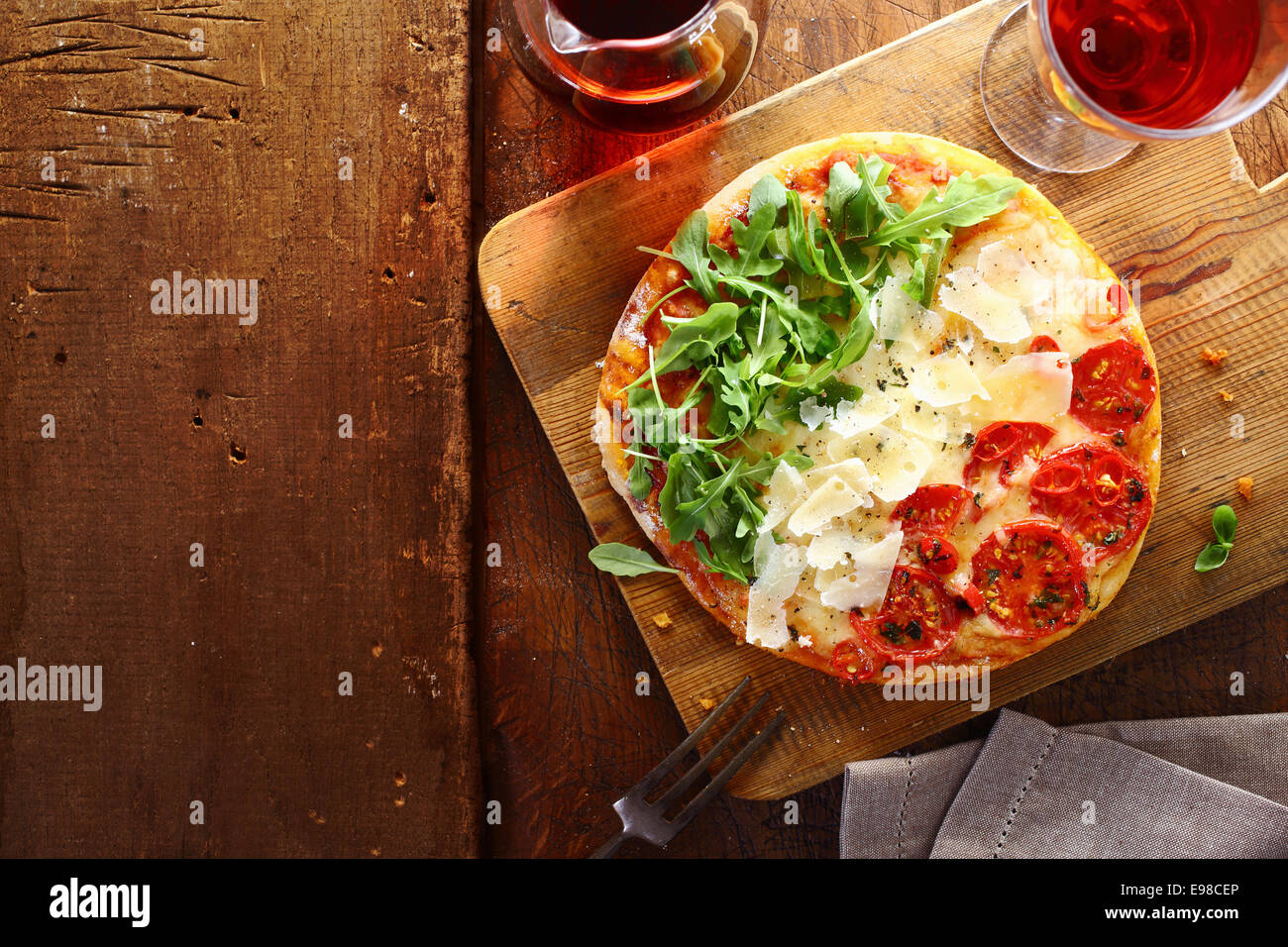 Italiano patriottica pizza tricolore con strisce di colore rosso, bianco e verde con i colori della bandiera nazionale formato da pomodoro, formaggio fresco e rucola utilizzato per il topping su un tavolo di legno con copyspace Foto Stock