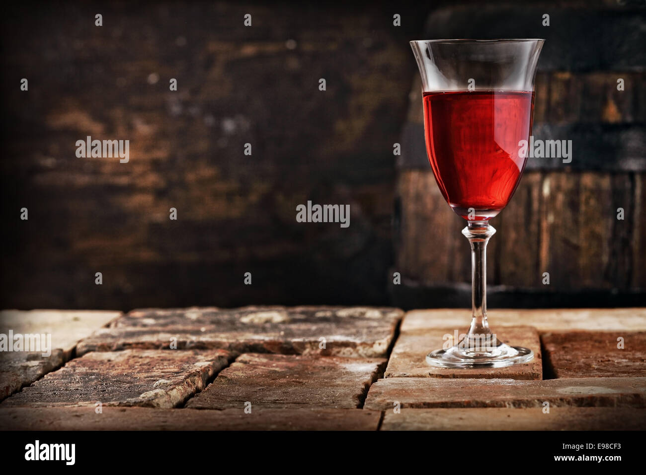 Un bicchiere di vino rosso su un vecchio tavolo rustico, profondità di campo. Foto Stock