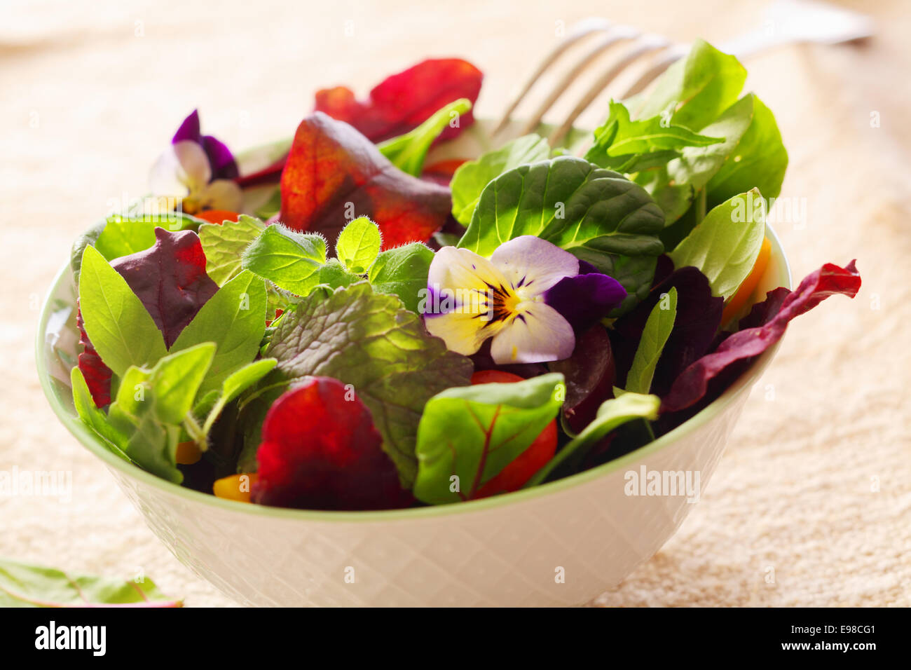 Erba fresca insalata con foglie verdi e i Nasturzi fiori servita in un bianco vaso in ceramica Foto Stock