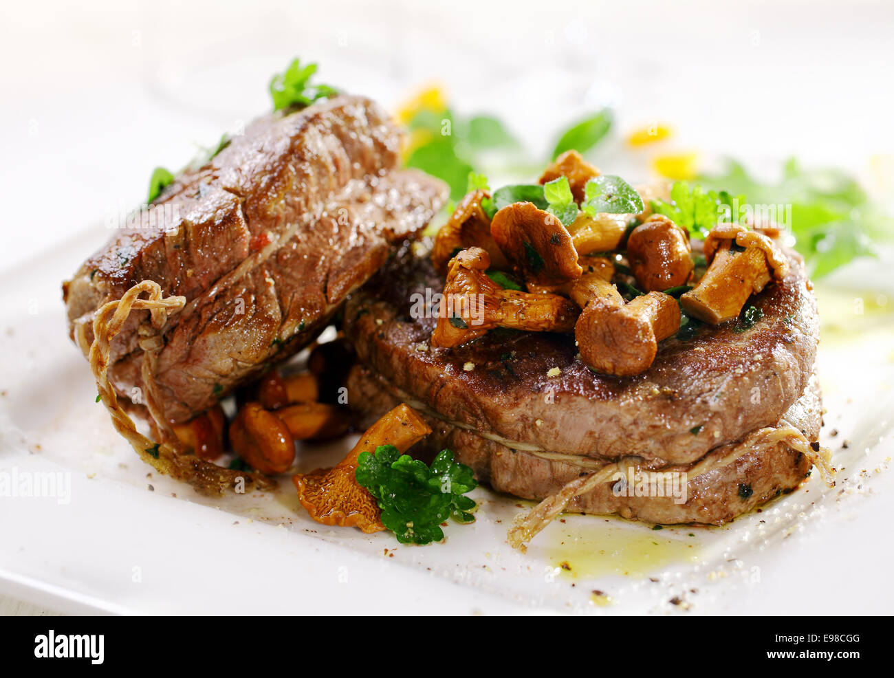 Spessore Gourmet succosa bistecca di filetto di medaglioni grigliate alla perfezione e servita rabboccato con la frittura di funghi selvatici e le erbe aromatiche Foto Stock