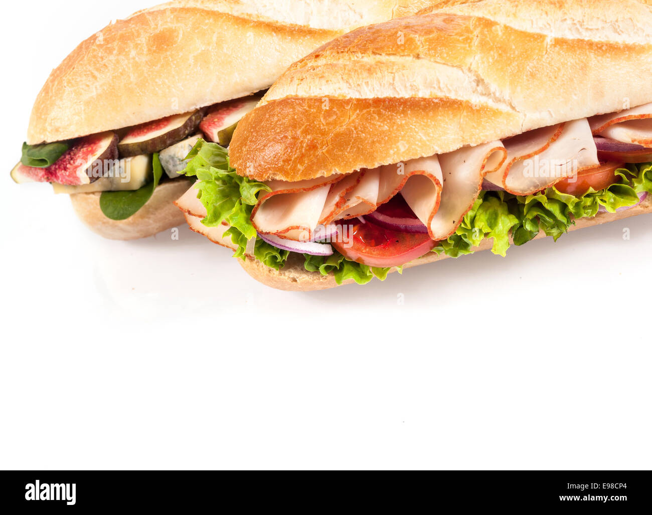 Due gustosi piatti gustosi crostini di baguette per un sano pranzo, uno con un formaggio blu, fichi e baby spinaci riempimento, e l'altra con pollo , pomodoro e lattuga frilly,vicino sul bianco con copyspace Foto Stock