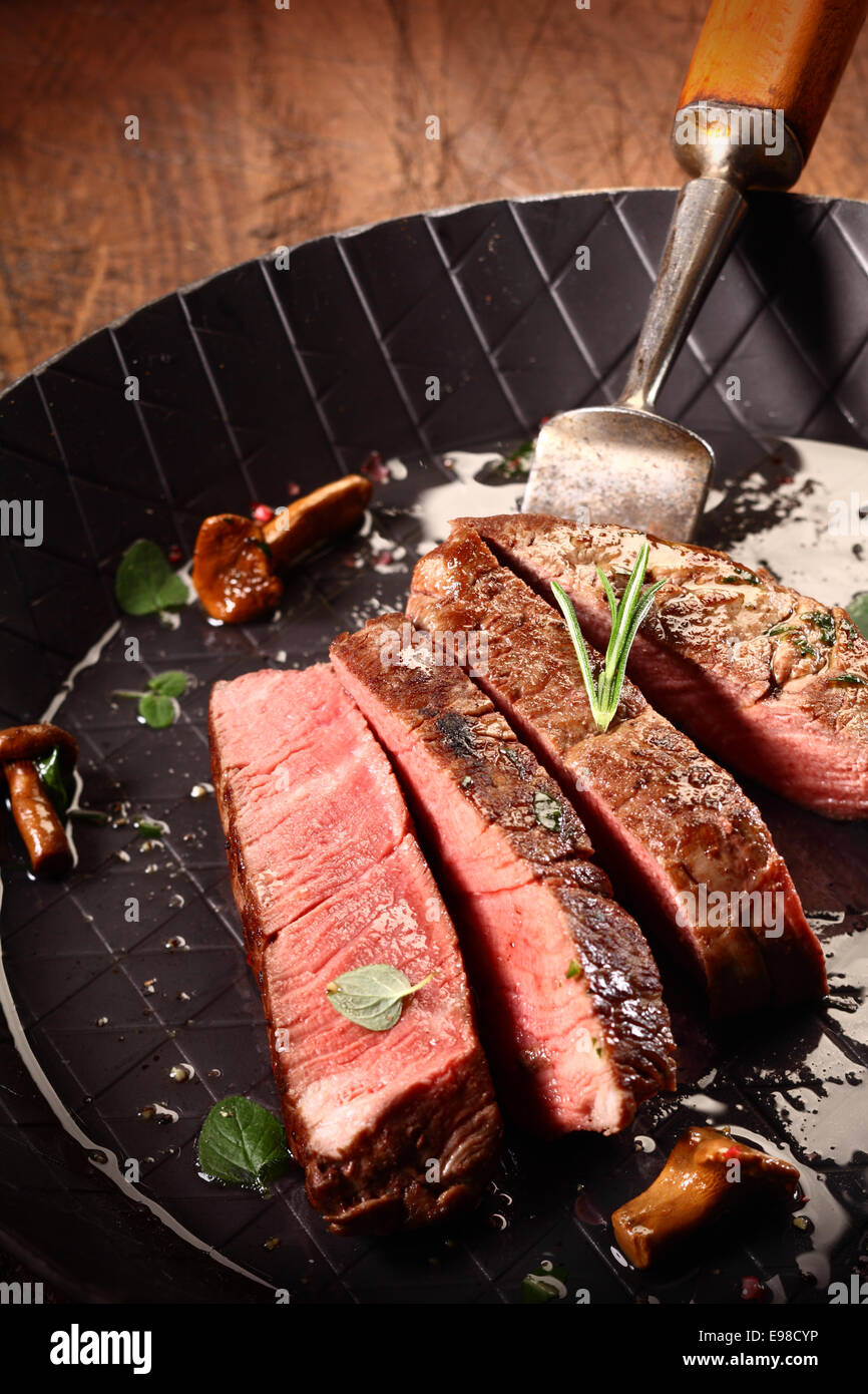 Raro cuocere carne di manzo magra bistecca di filetto o tagliata a fette in una teglia durante la cottura e la preparazione di un pasto gourmet Foto Stock