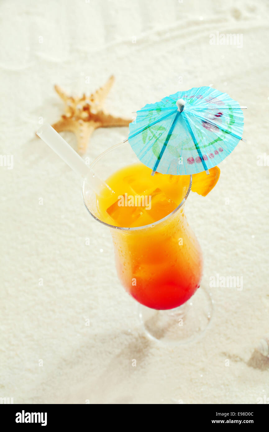 Cocktail tropicale con ombrello di carta sulla sabbia Foto Stock