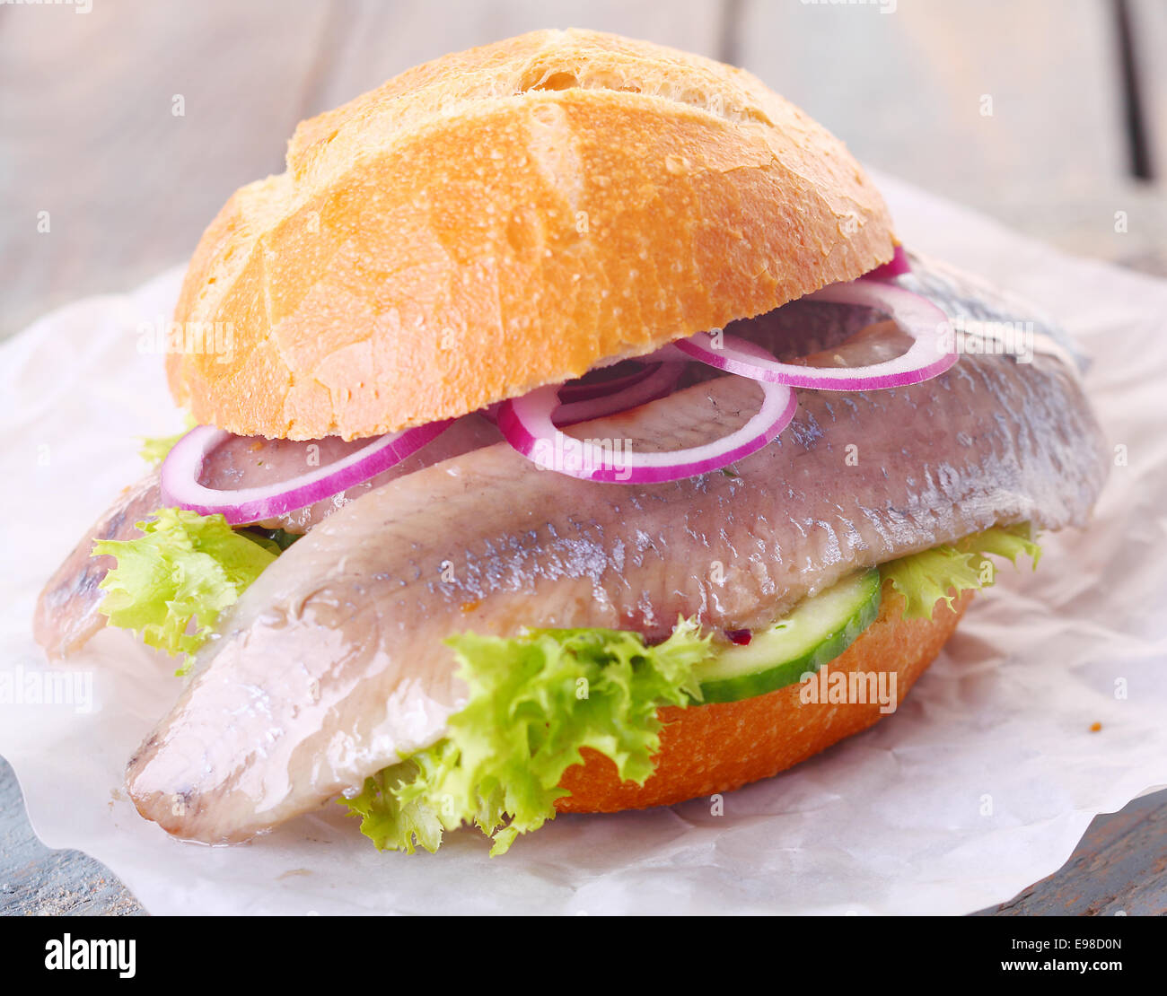 Vegetariano sano hamburger di pesce con un filetto di pesce a freddo su un letto di lattuga e di cetriolo e rabboccato con cipolla Foto Stock