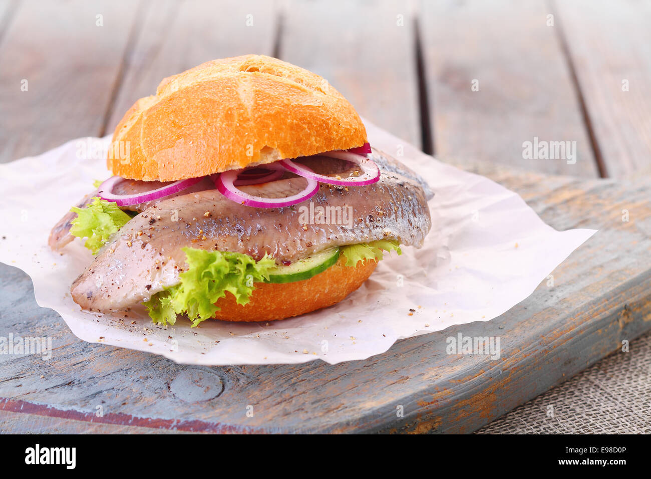 Hamburger di pesce con un pane appena sfornato crusty bun, filetto di pesce, cipolla e lattuga servita su un rustico di legno Foto Stock