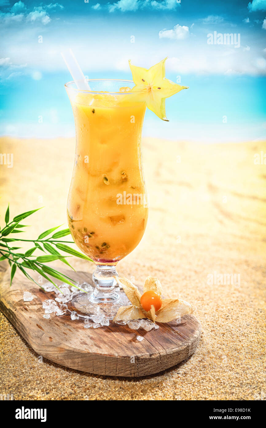 Elegante bicchiere di deliziosi cocktail di frutta su una spiaggia tropicale guarnito con anice stellato in piedi su una tavola di legno Foto Stock