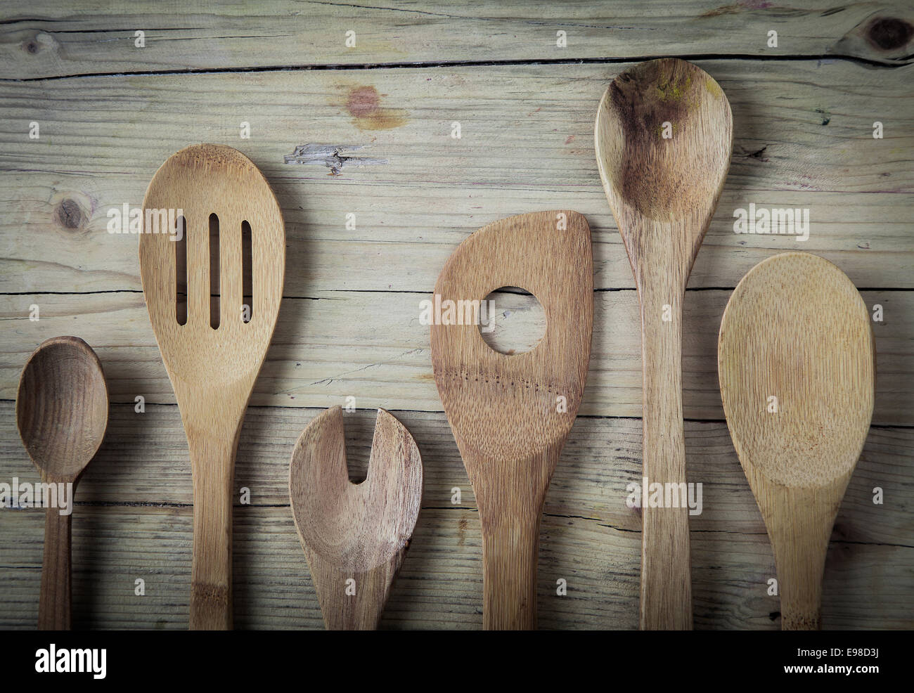 Un assortimento di vecchia cucina in legno utensili giacente su di una superficie di legno in un paese cucina pronti per la cottura o cucinare un pasto, vicino la vista aerea Foto Stock