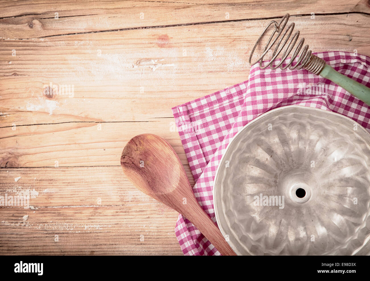 Vecchio metallo circolare stampo da forno per la cottura di una torta ad anello o flan giacente capovolto su un rosso fresco e bianco panno controllato su una tavola in legno rustico, vista aerea Foto Stock