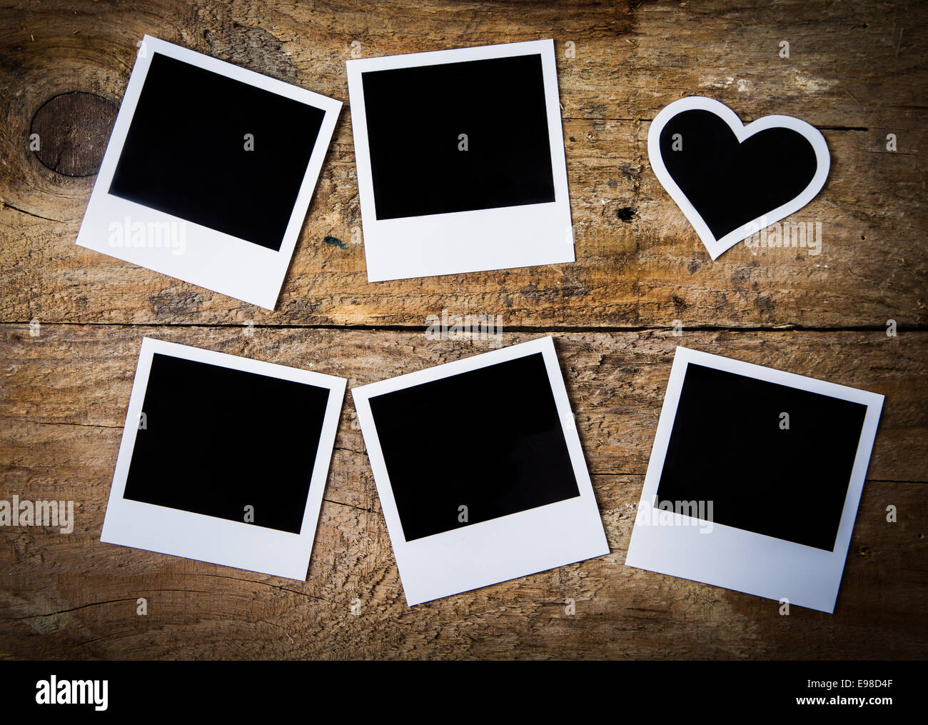 Sei vuoto instant photo frame giacente sul rustico weathered ruvida di tavole di legno, con uno a forma di cuore per un nostalgico Valentine o anniversario ricordo o memento , vista aerea Foto Stock