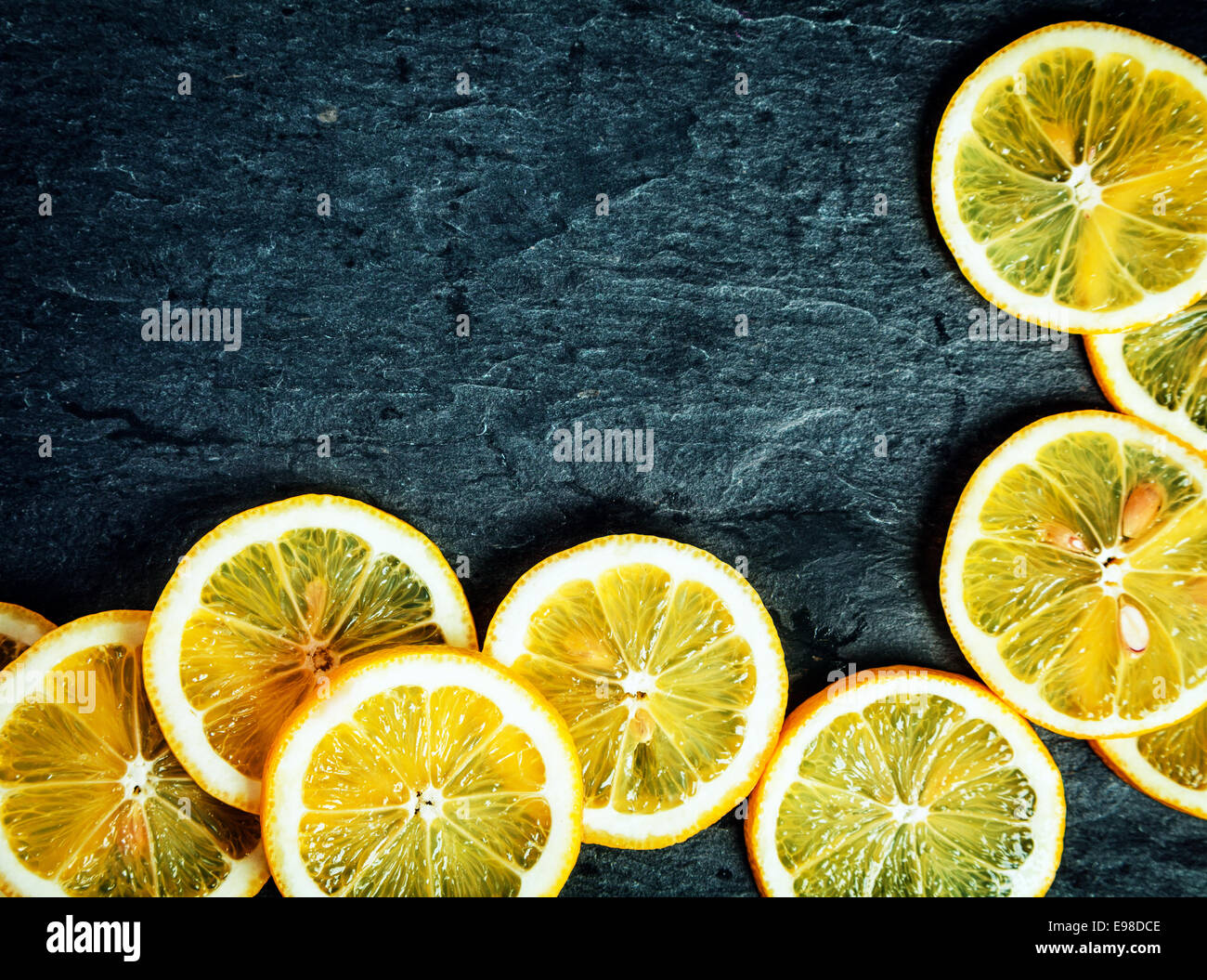 Fettine di arancio disposte in un angolo di decorazione su un grigio scuro ardesia testurizzata sfondo con copyspace per il testo Foto Stock