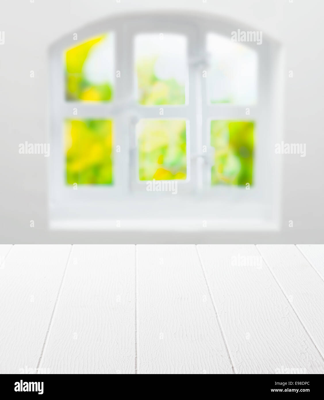 Vuoto bianco pulito tavolo da cucina nella parte anteriore di un cottage nel riquadro finestra arcuata con una vista del verde nel sole estivo come uno sfondo per il product placement Foto Stock
