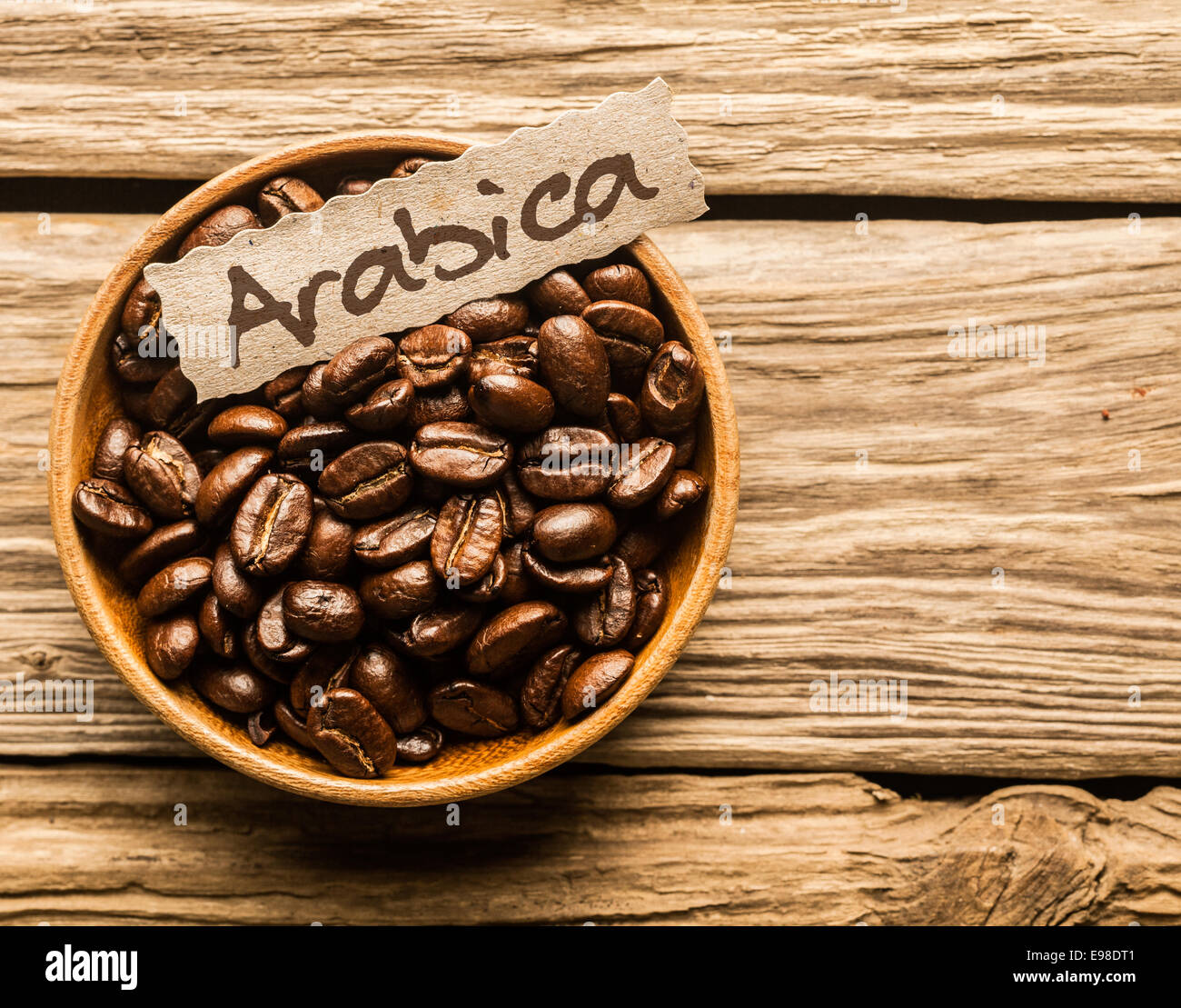 Ciotola piena di Arabica Coffee beans su un vecchio tavolo in legno Foto Stock