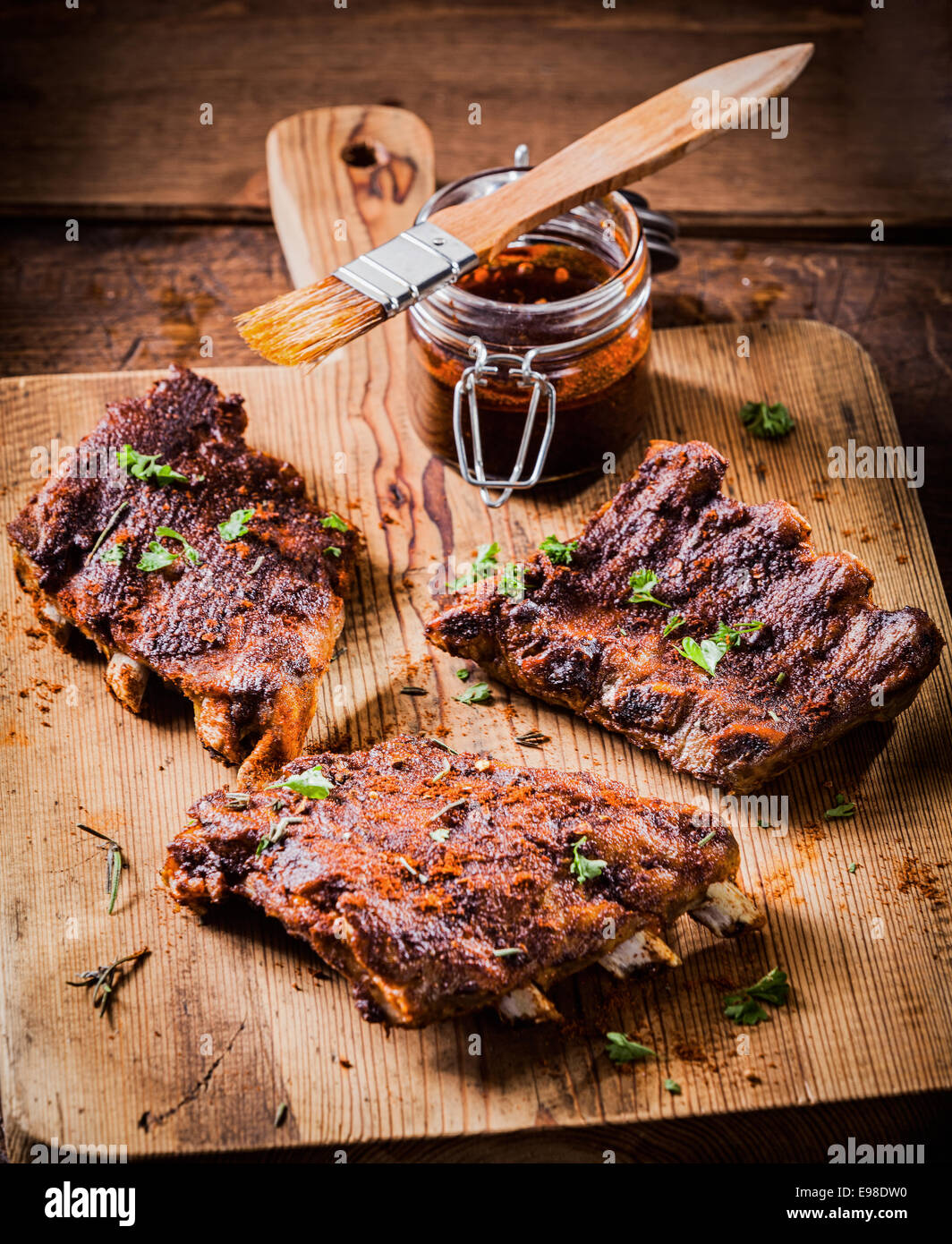 Tre porzioni di piccante grigliate di nervature imbastite con una saporita salsa aromatica e guarnita con erbe per un delizioso pasto Foto Stock