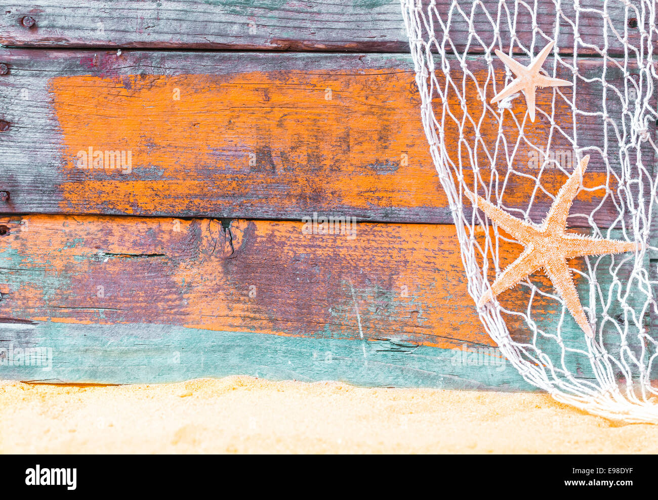 Starfish nautico con sfondo rustico weathered grunge dipinte di blu di tavole di legno, rete da pesca e la spiaggia dorata sabbia, copyspace per testo Foto Stock
