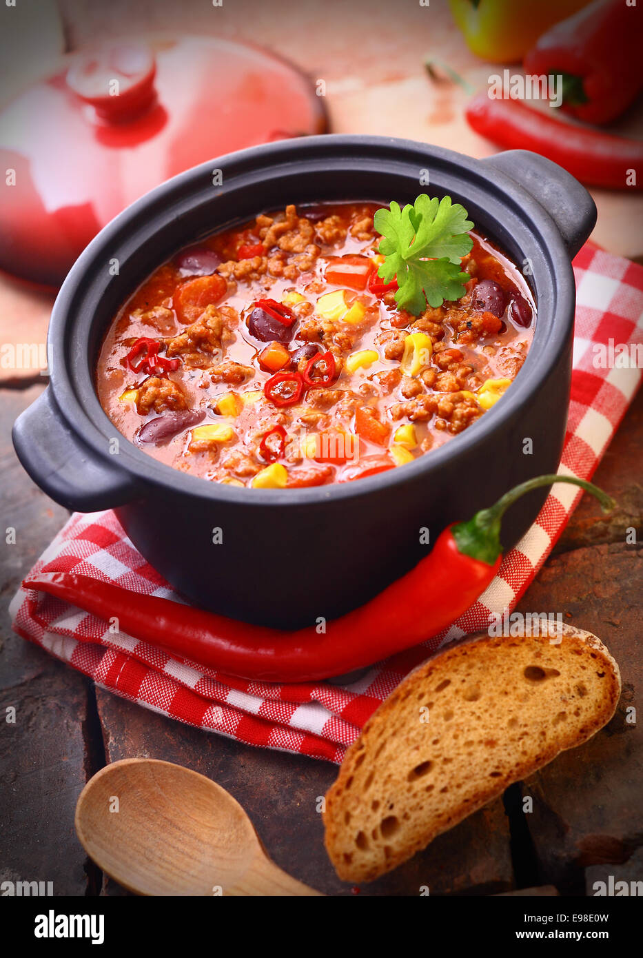 Piccante e speziato fatto fresco peperoncino Messicano ancora in una pentola in ferro, con un grezzo di peperoncino e una fetta di pane Foto Stock