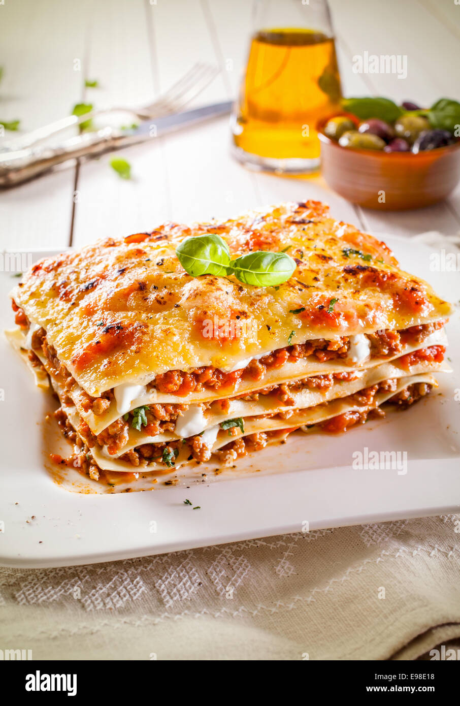 Porzione di tradizionali di frumento duro di lasagne con salsa bolognese, tritare la carne e il formaggio in strati alternati su una piastra bianca Foto Stock