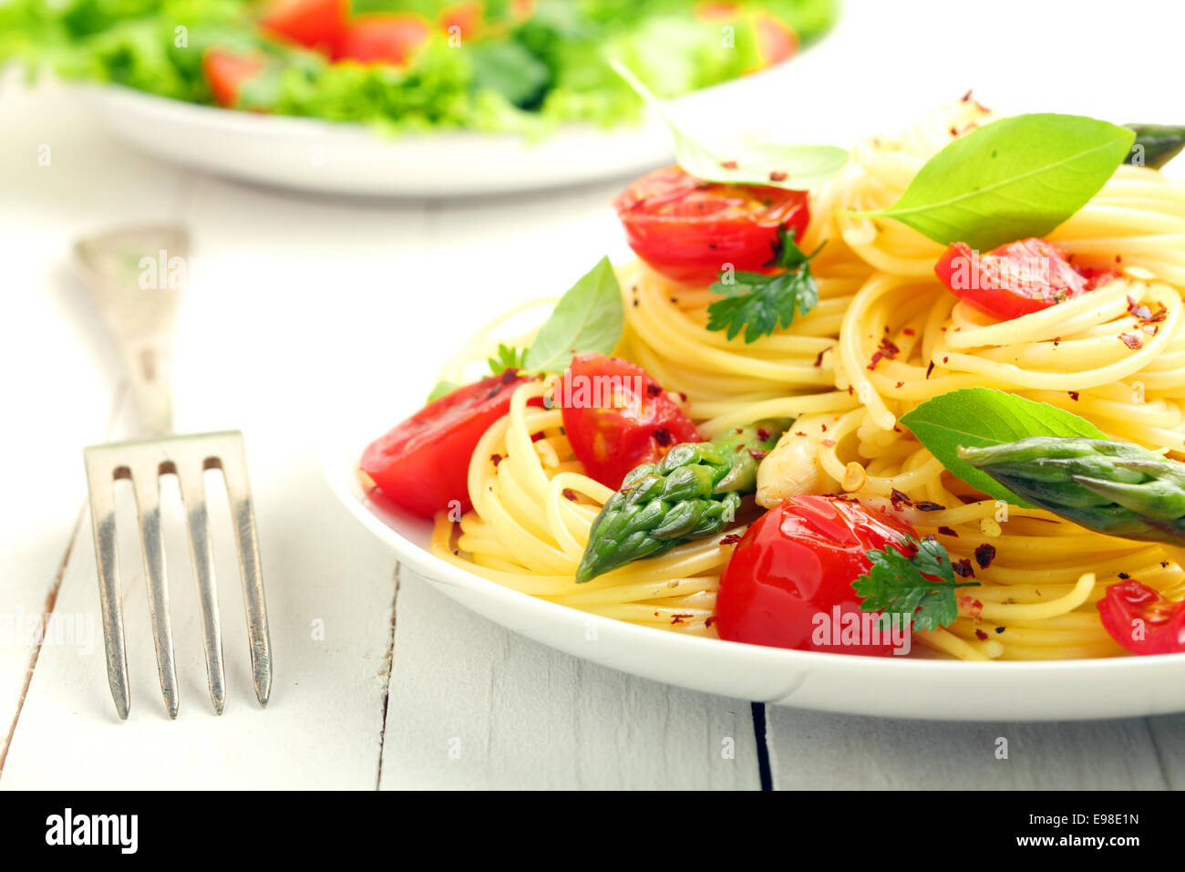 Avvolte cotto italiano spaghetti conditi con pomodoro e condito con prezzemolo fresco tritato e le foglie di basilico Foto Stock