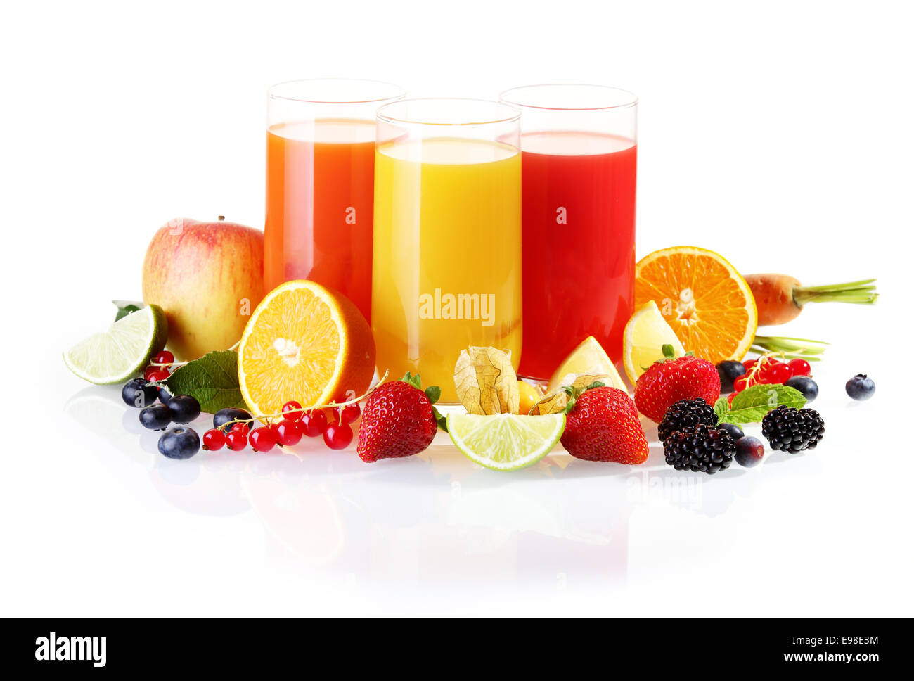 Disposizione colorati di frutta fresca comprese le bacche, gli agrumi e le mele con bicchieri di succo liquidised per un sano inizio di giornata Foto Stock