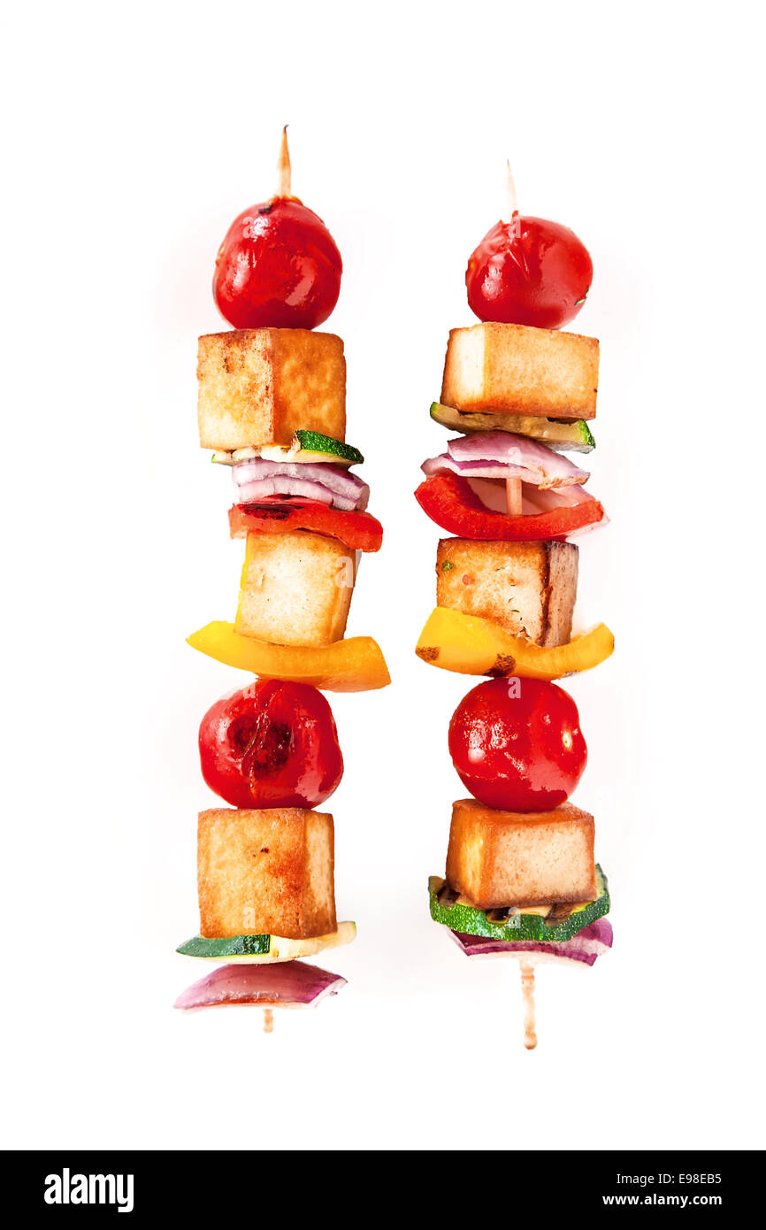 Due coloratissimi sano affumicato grigliato tofu e spiedini di verdure su spiedini di legno con pomodoro ciliegino, pepe e cipolla isolato su bianco Foto Stock