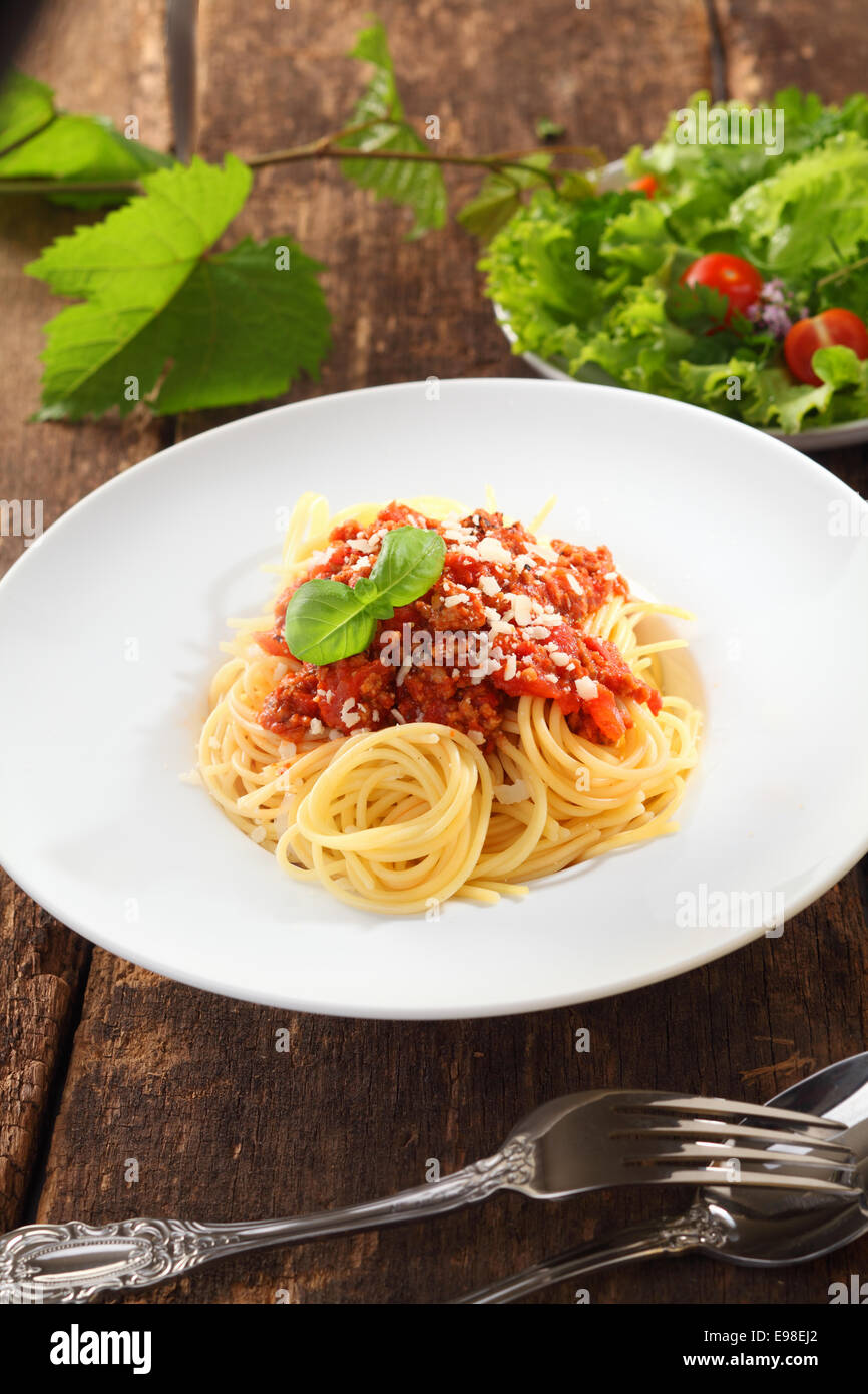 Piastra di sano italiano spaghetti con salsa bolognese servito con una fresca insalata verde Foto Stock