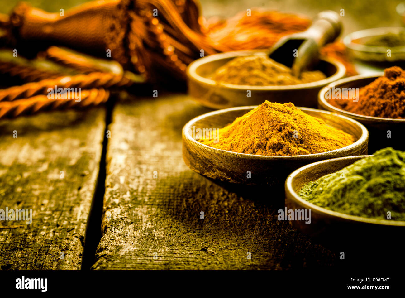 Cucina asiatica con un basso angolo di visione delle ciotole di spezie colorate con messa a fuoco per una ciotola di curcuma in base di curry in polvere Foto Stock