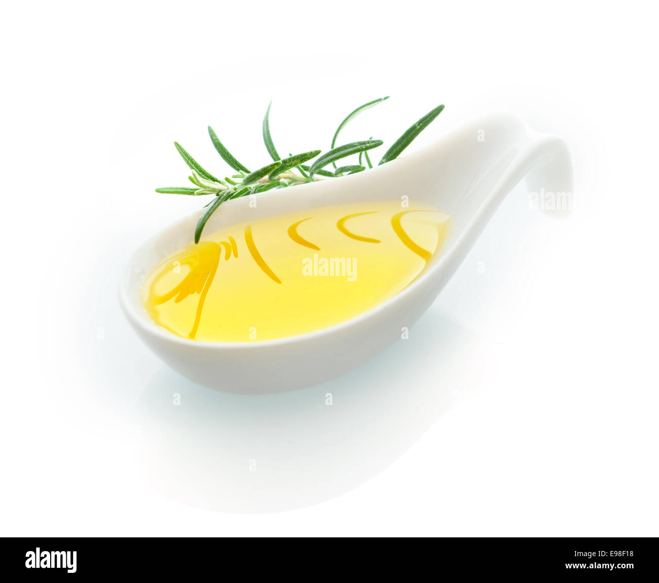 Close up di un cucchiaio di ceramica riempito con golden olio vergine di oliva con un rametto di rosmarino fresco su sfondo bianco Foto Stock