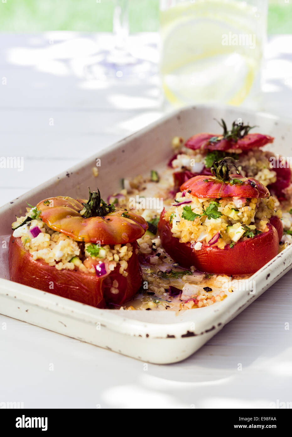 Pomodori al forno con ripieno salato, formaggio ed erbe serviti in un vecchio forno piatto come un gustoso antipasto per un pasto Foto Stock