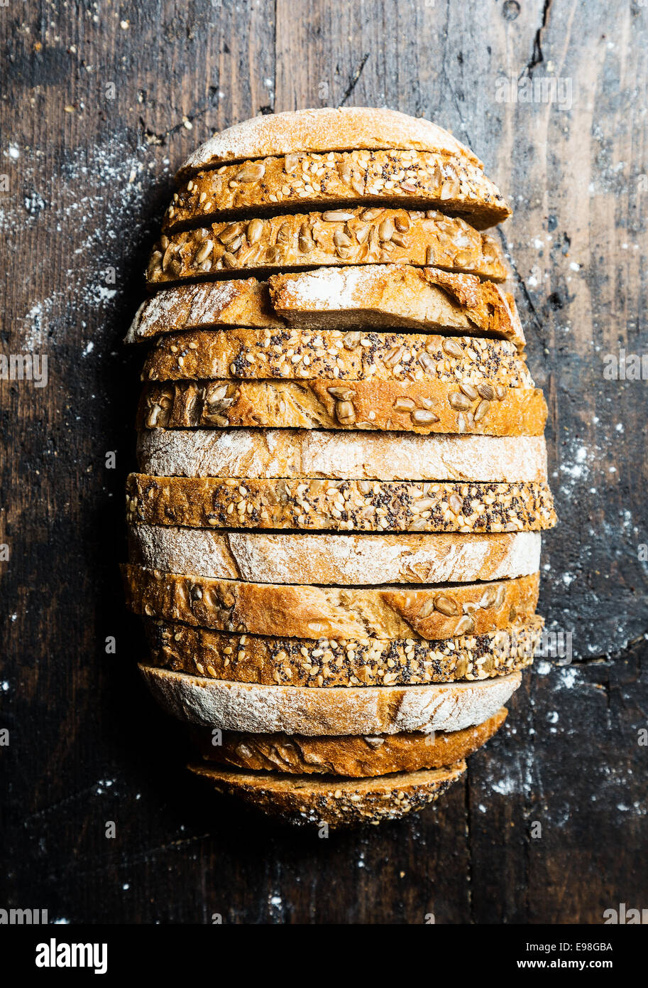 Interessante pagnotta di pane costituito da strati alternati di marrone pane integrale con i semi sulla crosta e il pane di segale è vista dal di sopra su un vecchio superficie di legno Foto Stock