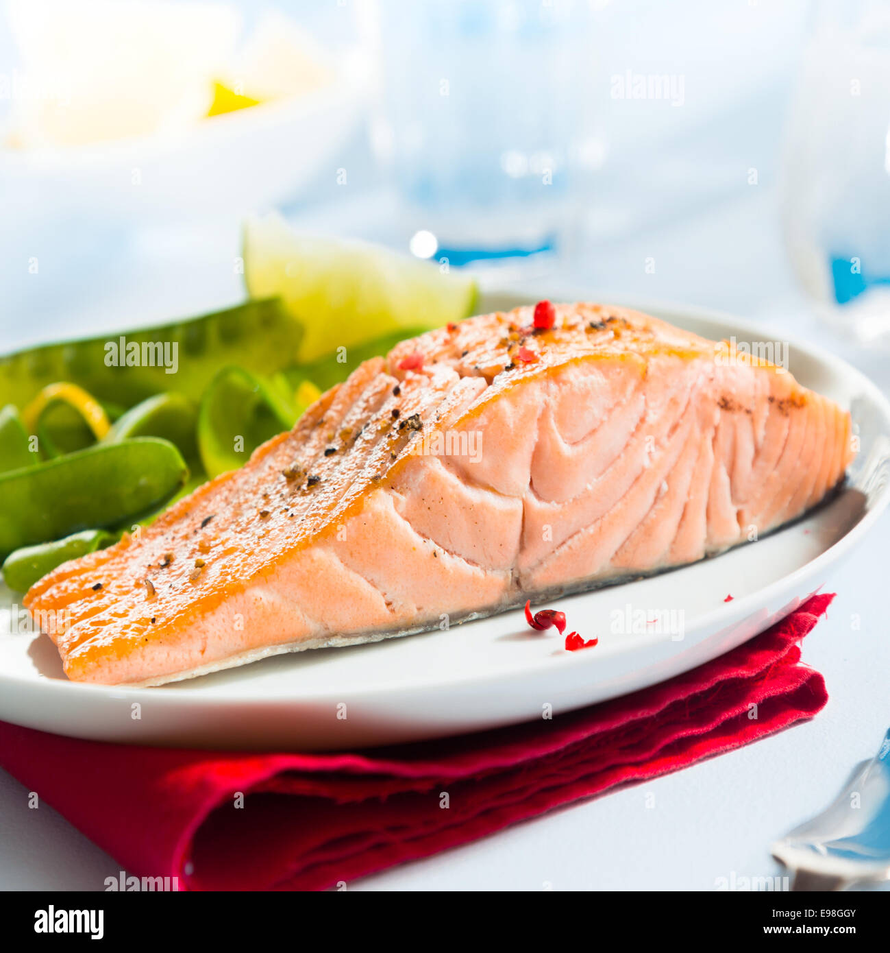 Sana rosa gourmet bistecca di salmone ricco di omega 3 servita con fresco verde taccole piselli e limone, vicino che mostra la consistenza del pesce Foto Stock