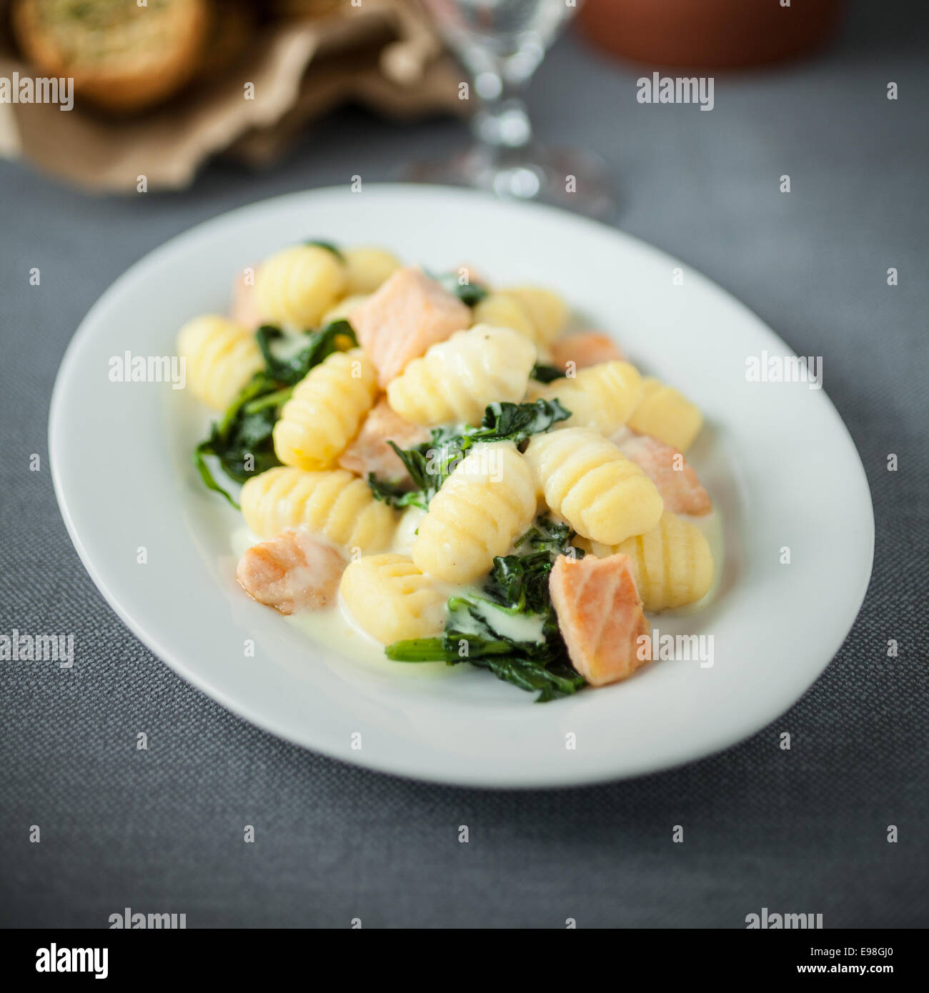 Il salmone è servita con italiano saltato gnocchi di pasta e basilico su un piatto di forma ovale per la deliziosa cucina mediterranea. Foto Stock