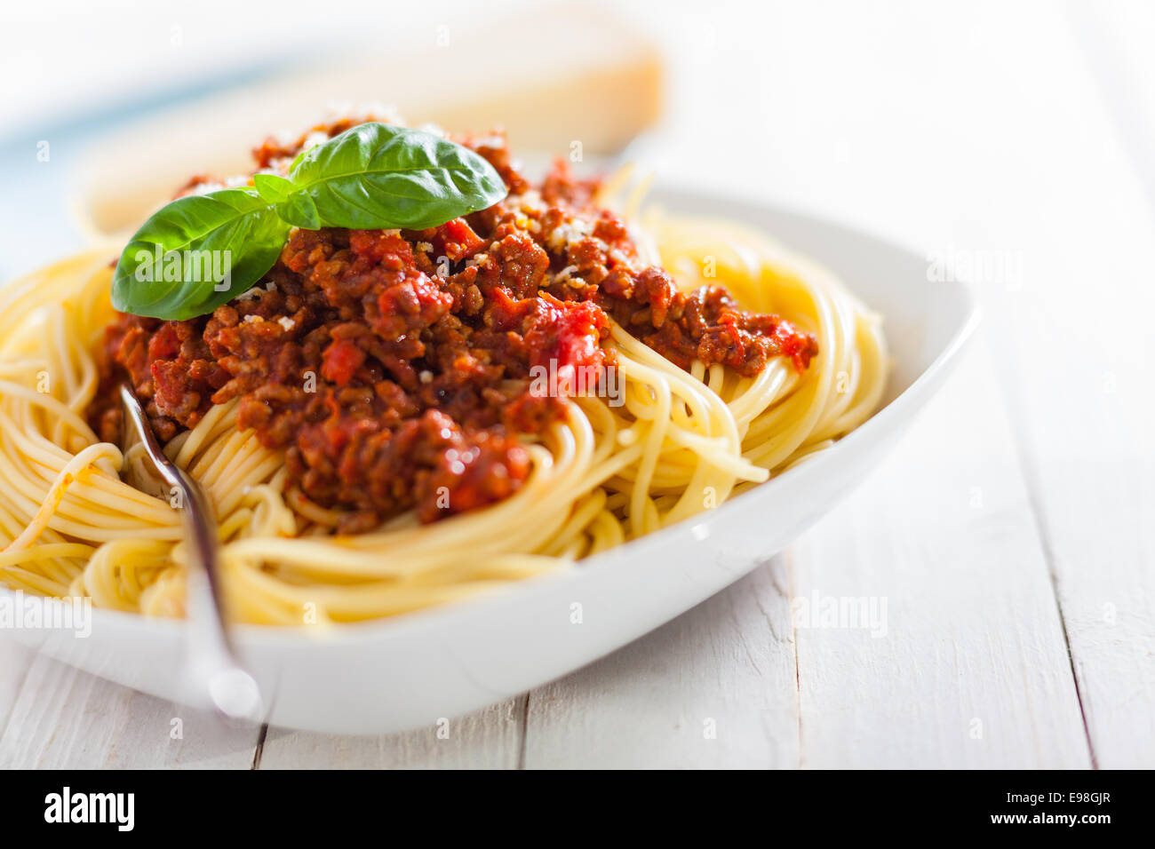 Piatto di spaghetti italiano con ricchi a base di pomodoro salsa bolognese guarnite con foglie di basilico fresco per una sana mediterraneo Foto Stock