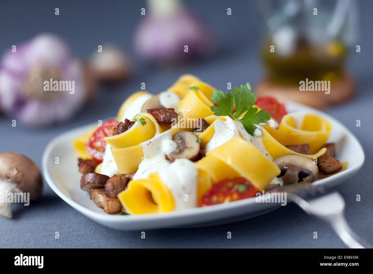 La deliziosa cucina italiana di pappardelle o la pasta cotta con i funghi e i pomodori e spruzzata con una crema stagionato Foto Stock