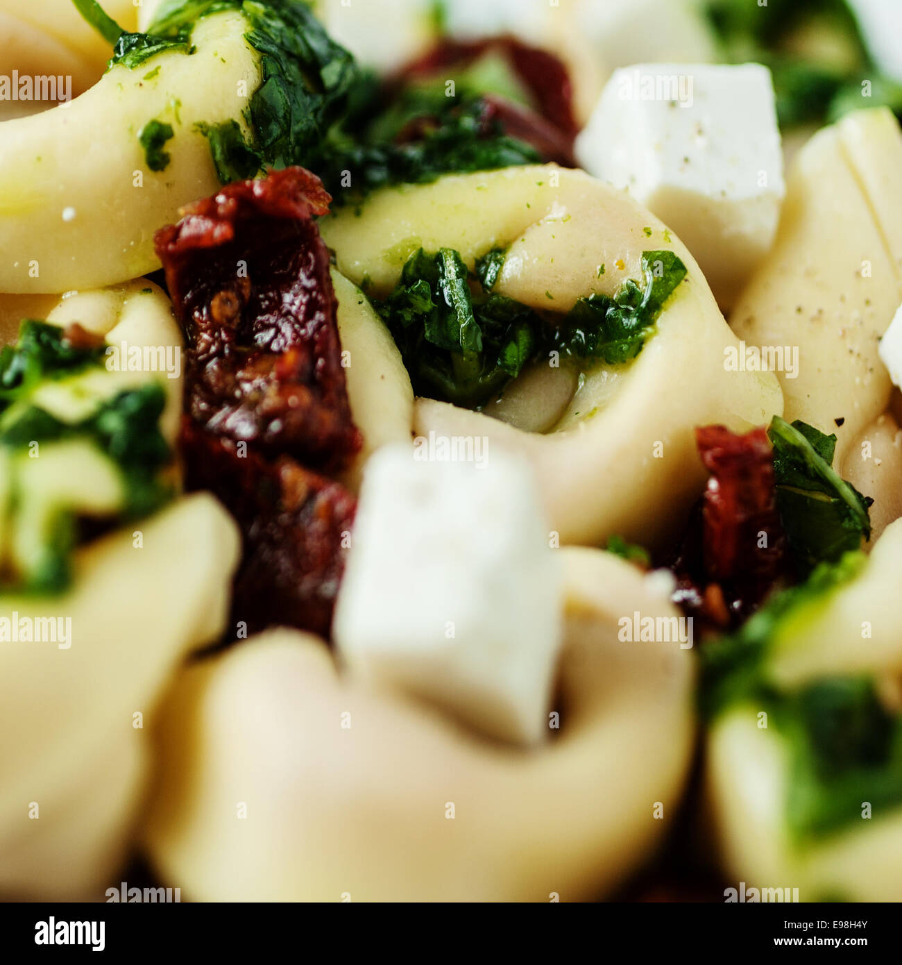 Una gustosa cucina italiana con una vista ravvicinata di tortelli ripieni di pasta con feta e pesto di basilico in formato quadrato Foto Stock