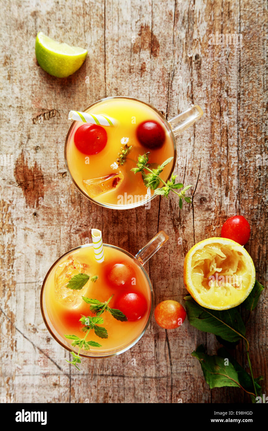 Bicchieri di Frutta estiva fresca cocktail miscelati con succhi di frutta guarnito con mirtilli rossi freschi e le erbe su una tavola in legno rustico, vista aerea Foto Stock