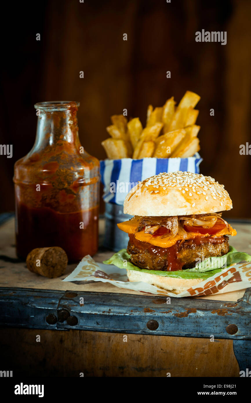 Gustosi piatti a mano Burger Quarter Pounder con patatine e salsa a lato e in stile rustico. Foto Stock