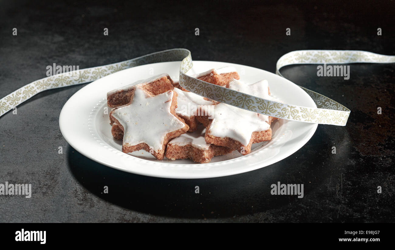 La piastra dei tradizionali biscotti di Natale nella forma di un bianco stella Vetrata decorativa con un nastro argentato per una festa di sfondo per le vacanze Foto Stock