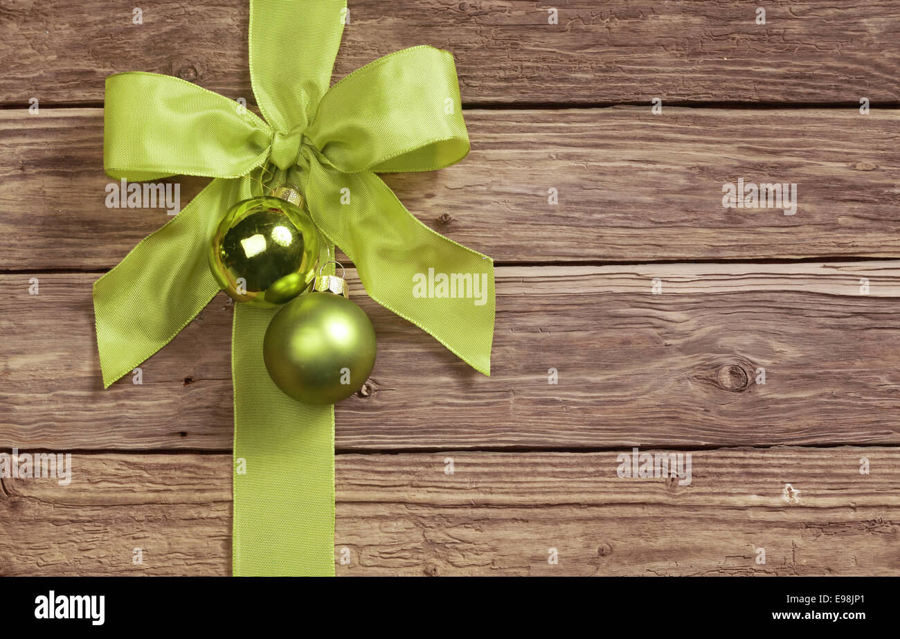 Decorativo arco verde decorato con due pallina Natale ornamenti su uno sfondo di legno con copyspace per il messaggio di saluto stagionale Foto Stock