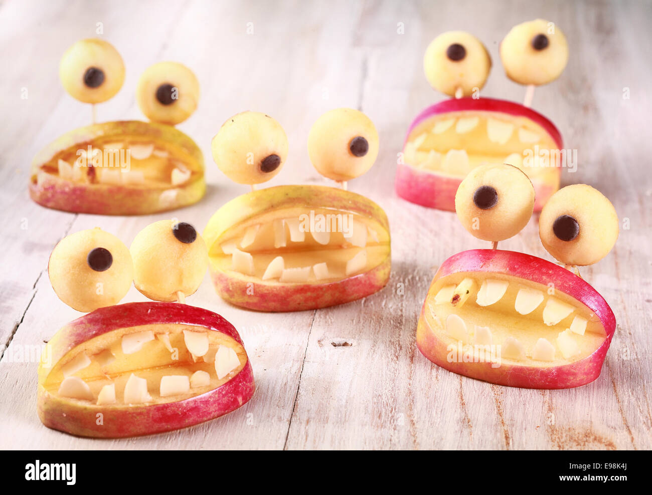 Spooky Halloween party favori o decorazioni realizzate da mele fresche e di pasta in forma di bocche aperte foderato con denti e rabboccato con round googly occhi su un tavolo rustico, creativo di artigianato del paese Foto Stock