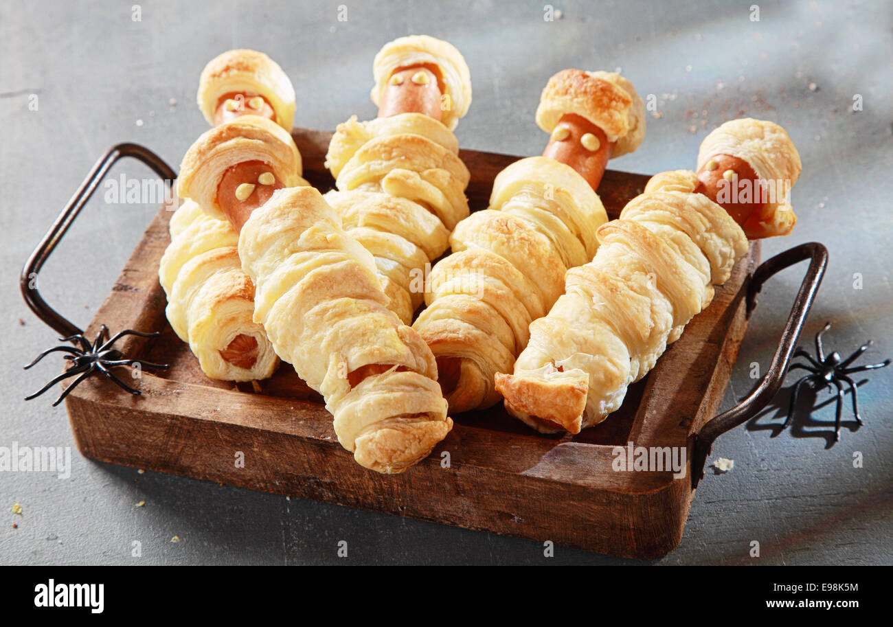 Cinque Weiner mummie avvolto in pasticceria sul vassoio per la festa di Halloween antipasti Foto Stock