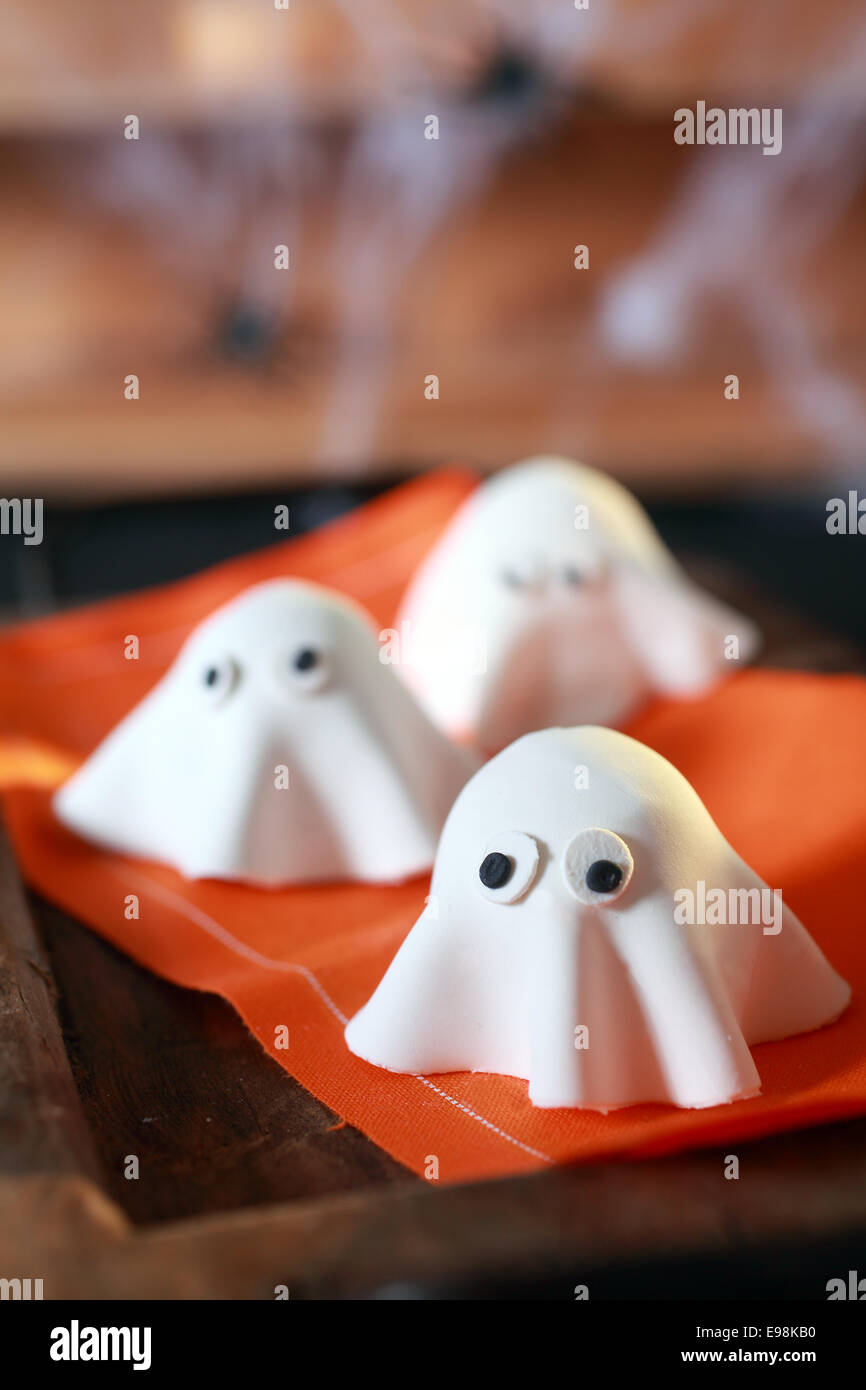 Festa di Halloween decorazioni ripiegato dalla pasta in forma di poco spaventosi fantasmi con grandi occhi su un tovagliolo arancio con Foto Stock