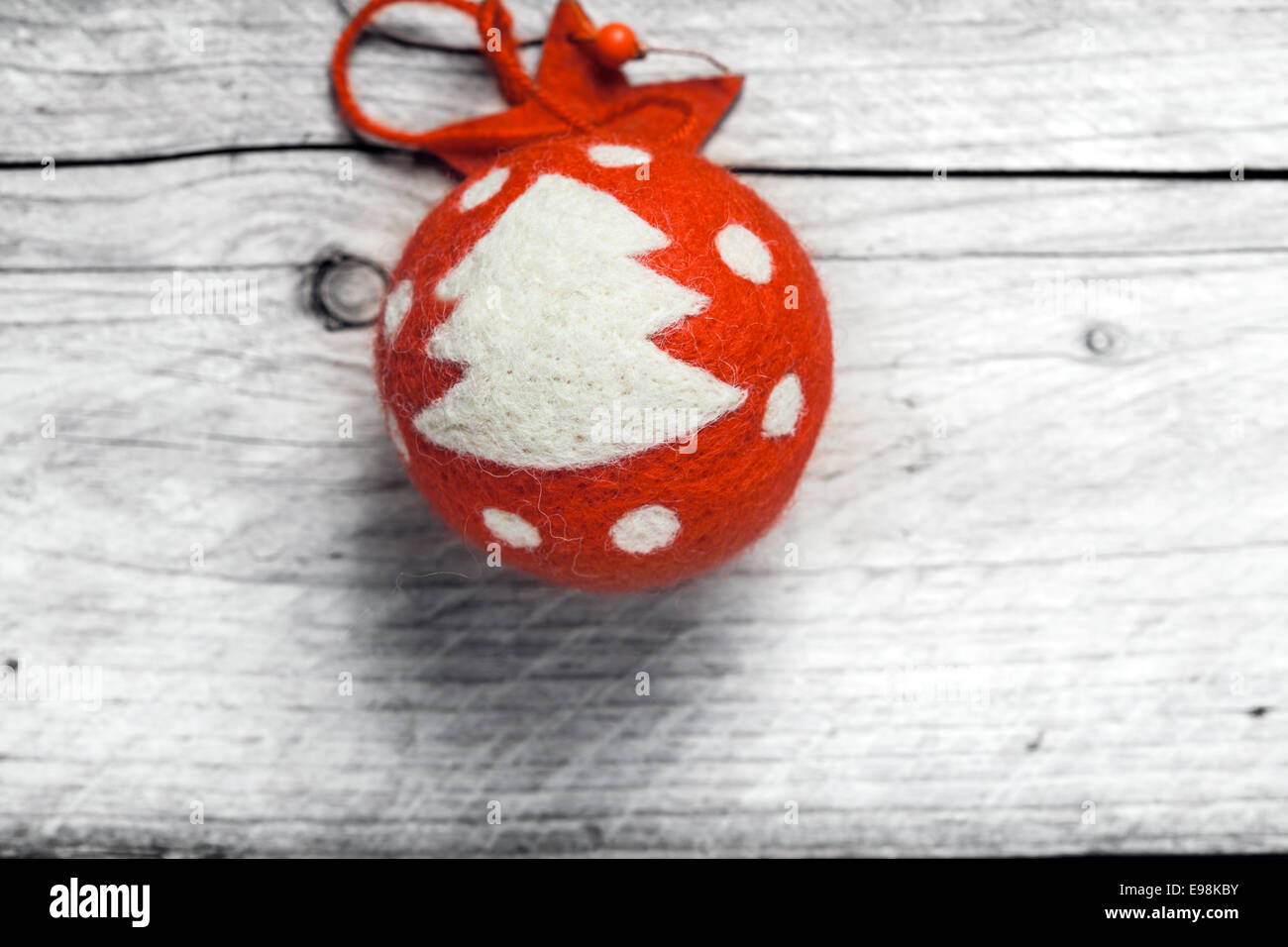 Rosso Pallina natale decorato con un albero e pois appeso contro uno spiovente parete in legno in un rustico di Natale il concetto di sfondo Foto Stock