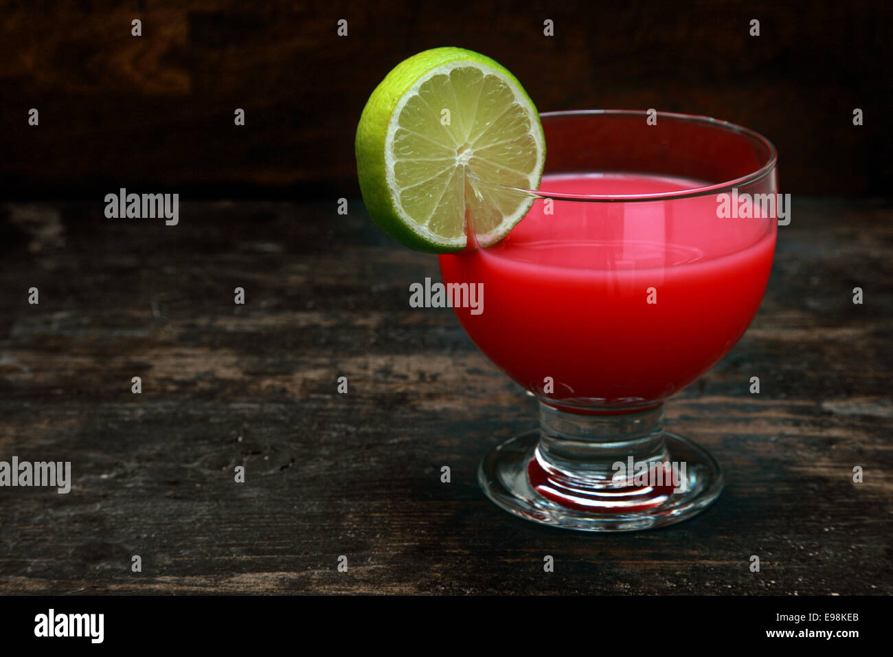 Bloody Mary cocktail di pomodoro guarnita con il limone in piedi su un vecchio bar in legno contro contro uno sfondo scuro con copyspace Foto Stock