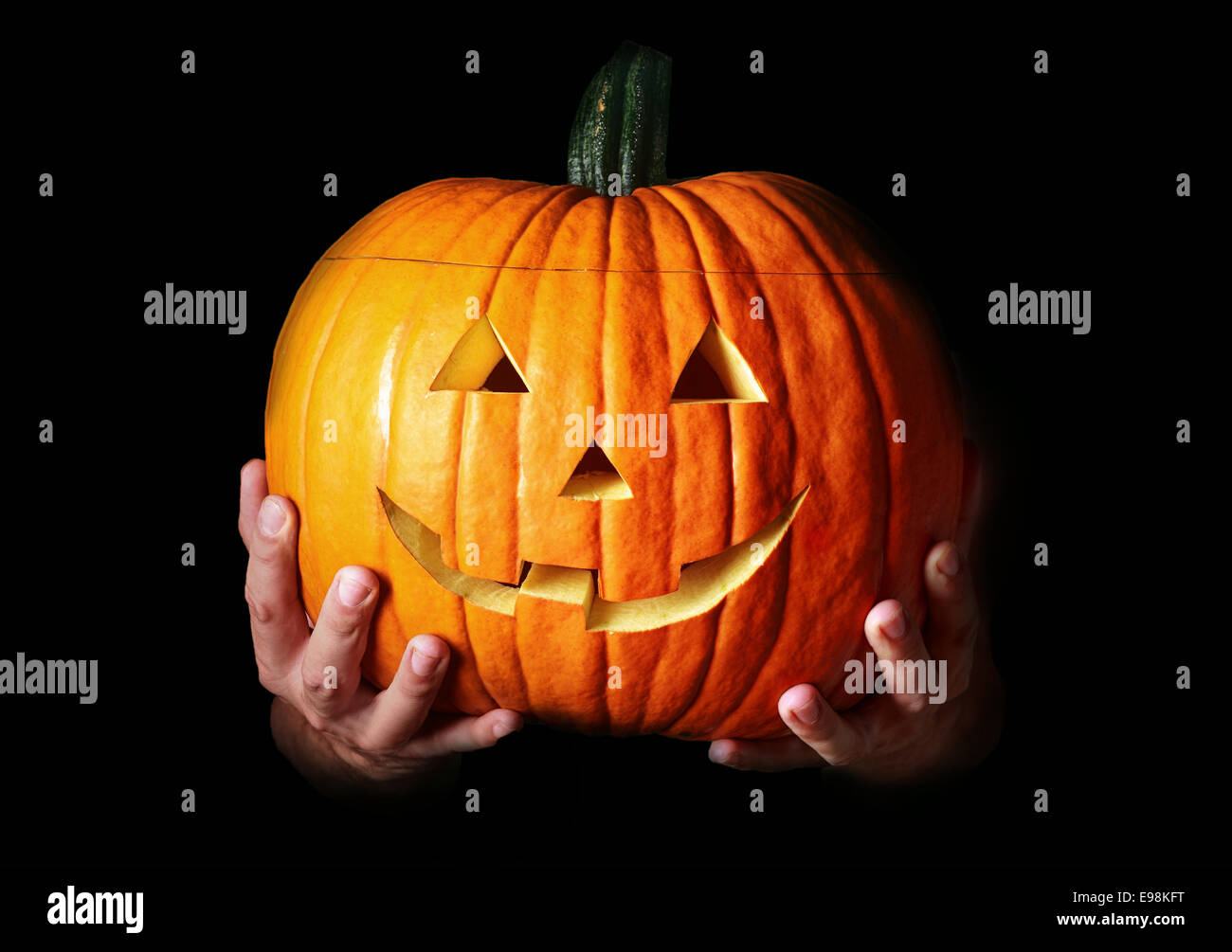 Mani tenendo un tradizionale Halloween creepy scolpiti zucca, con copia spazio su nero Foto Stock