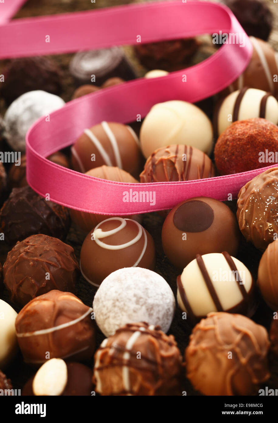 Una decorazione a nastro rosa si trova twirled oltre a mano cioccolatini sferica con diverse configurazioni in un dono e celebrazione concept Foto Stock