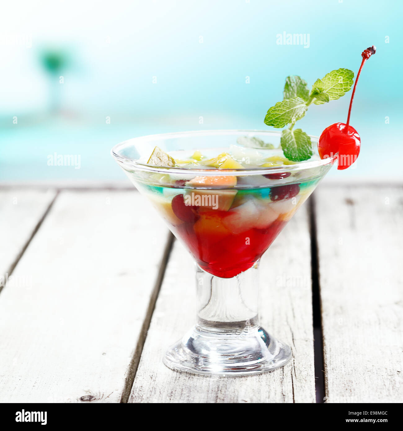 La frutta tropicale ciotola cocktail con curacao blu su un ponte in spiaggia con copyspace Foto Stock