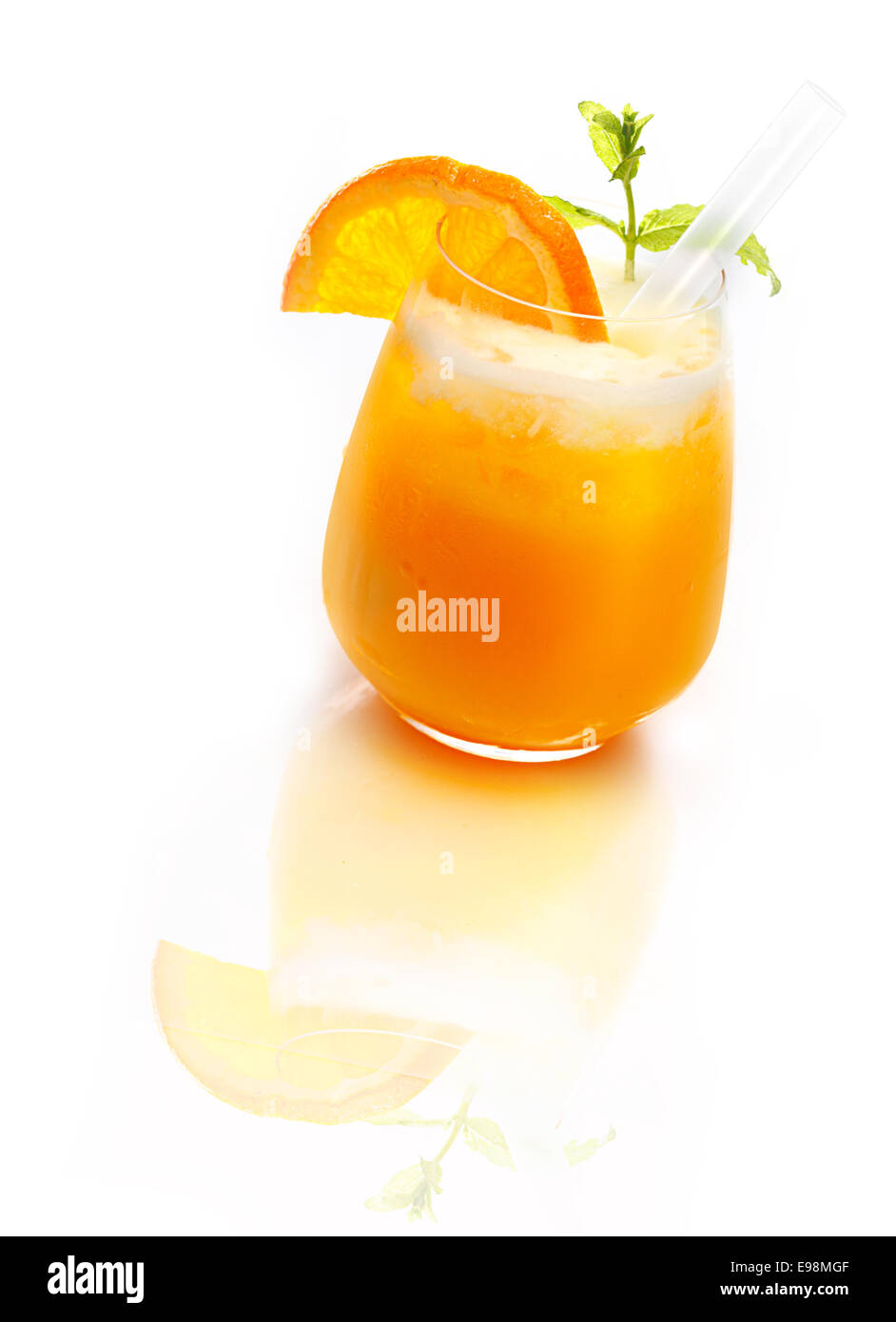 Bicchiere di rinfrescante cocktail arancione e rabboccato con ghiaccio su una superficie bianca riflettente Foto Stock